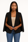 Femme portant un blazer cape noir élégant avec un top beige et un jean.