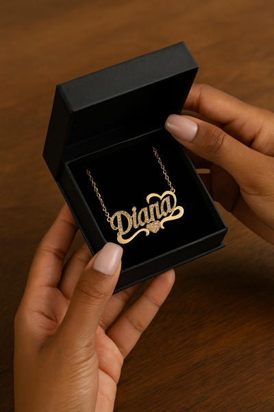 Collier prénom personnalisé Diana doré tenu par des mains féminines manucurées, bijou élégant en acier inoxydable.