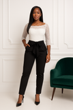 Combi-pantalon chic noir avec haut en dentelle blanche, manches longues et ceinture élégante.