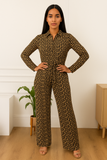 Femme élégante portant une combinaison chic noire et dorée à motifs géométriques, vue de face.