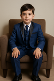 Garçon assis élégamment vêtu d’un costume bleu marine 3 pièces.