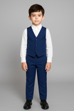 Garçon en gilet bleu royal assorti avec chemise blanche élégante.