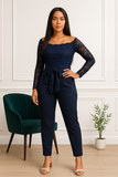 Combinaison élégante bleu marine en dentelle manches longues, femme posant avec main sur la hanche.