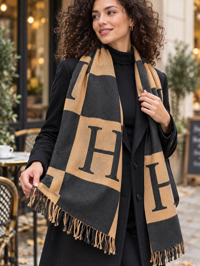 Femme portant une grande étole camel et noire à motifs géométriques, vue de face