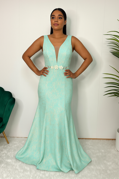 Femme portant une robe de soirée sirène turquoise et dorée vue de face, avec ceinture florale blanche.