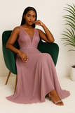 Femme assise en robe de soirée mauve longue à haut pailleté et décolleté en V.
