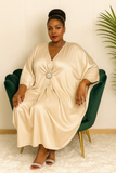 Robe caftan satin beige fluide – détail du décolleté en V et de la broche