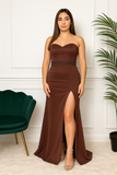 Femme portant une robe longue bustier marron avec fente, debout de face.