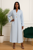 Pose élégante d’une femme en robe longue rayée bleu ciel à boutons dorés.