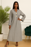 Pose moderne d’une femme en robe longue rayée grise à boutons dorés.