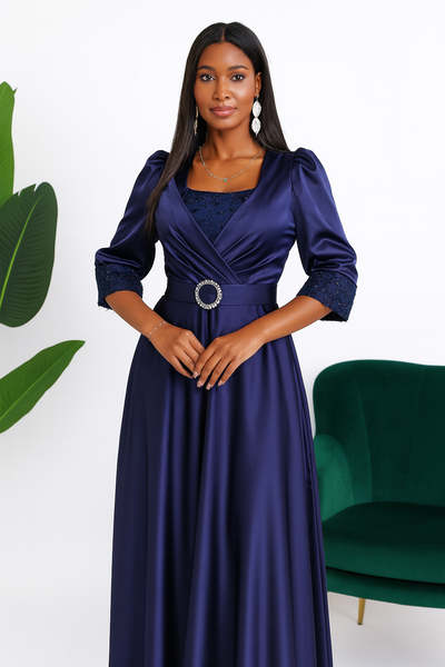 Détail du haut de la robe de soirée bleu nuit en satin, avec décolleté croisé et ceinture bijou.