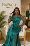 Robe de soirée longue verte en satin fluide avec haut en sequins, mannequin assise sur fauteuil de luxe dans boutique Hafsoit Mode