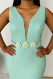 Gros plan sur la ceinture florale à trois fleurs avec strass, sur robe turquoise à reflets dorés.